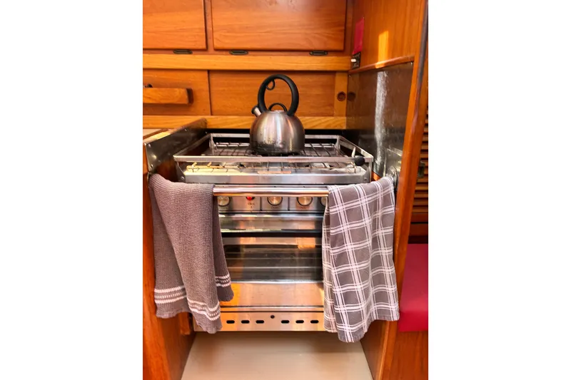Slide: The Image of Compact boat kitchen with stove, kettle, and towels in a 1989 CAL 39 model. - 19