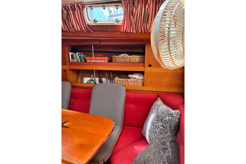 Slide: The Image of Cozy interior of 1989 CAL 39 sailboat with red seating, wooden shelves, and nautical decor. - 25