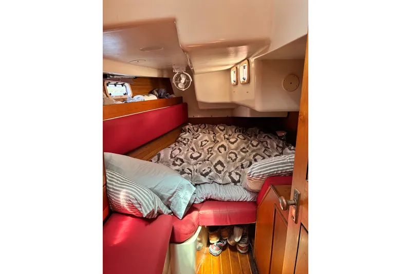 Slide: The Image of Cozy cabin interior of 1989 CAL 39 sailboat with red seating and patterned bedding. - 24