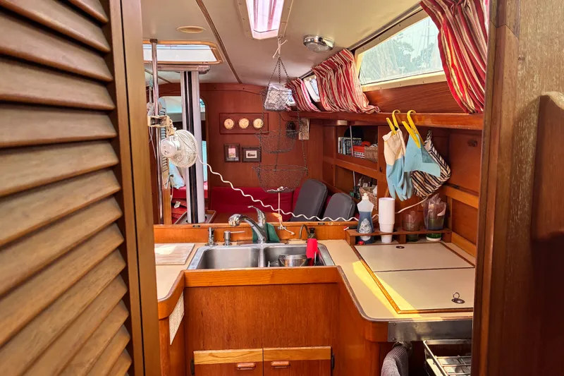 Slide: The Image of Interior of a 1989 CAL 39 sailboat with wooden cabinetry and striped curtains. - 16