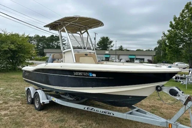 The Image of 2012 Scout 210 XSF boat on trailer, parked outdoors, with overcast sky. - 0