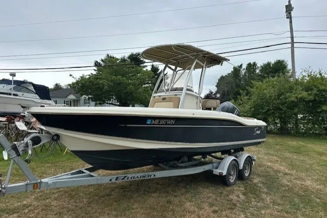 Slide: The Image of 2012 Scout 210 XSF boat on trailer, parked on grass, with overcast sky. - 4