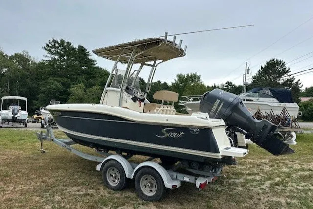 Slide: The Image of 2012 Scout 210 XSF boat on trailer, parked outdoors with trees in background. - 3