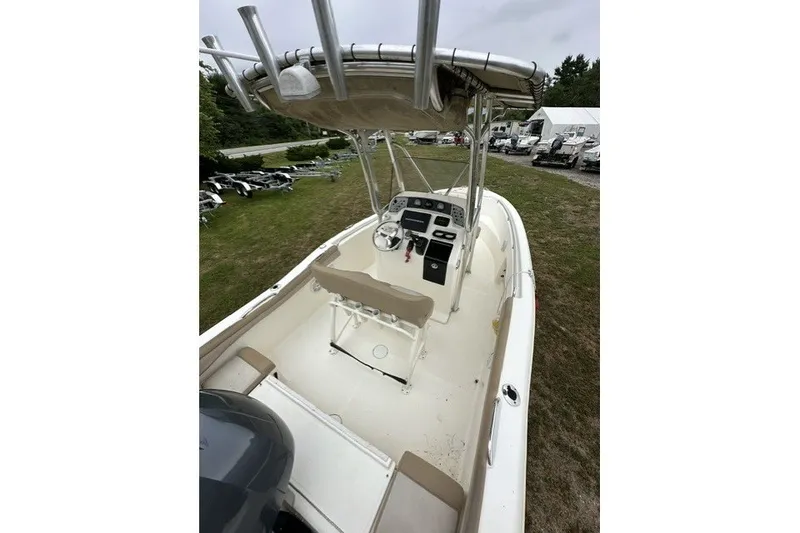 Slide: The Image of 2012 Scout 210 XSF boat with center console and T-top, parked on grass. - 17