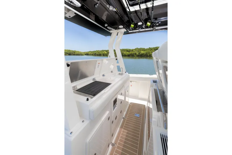 Slide: The Image of 2027 Pursuit S 388 Sport boat interior with grill and storage, overlooking serene water. - 16