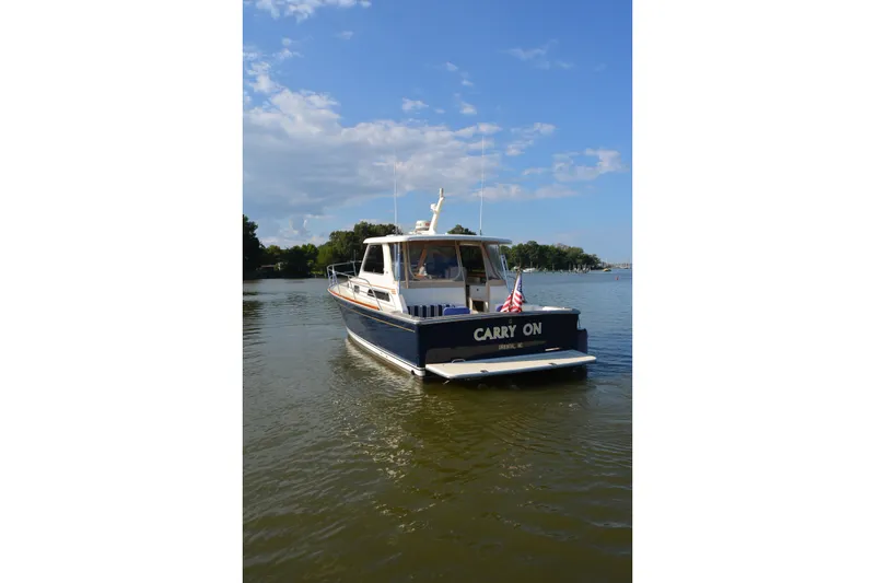 Slide: The Image of 2005 Sabre 38 Express boat named "Carry On" on calm water under blue sky. - 3