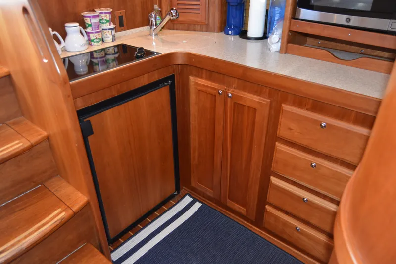Slide: The Image of 2005 Sabre 38 Express yacht kitchen with wooden cabinetry, compact fridge, and countertop appliances. - 68