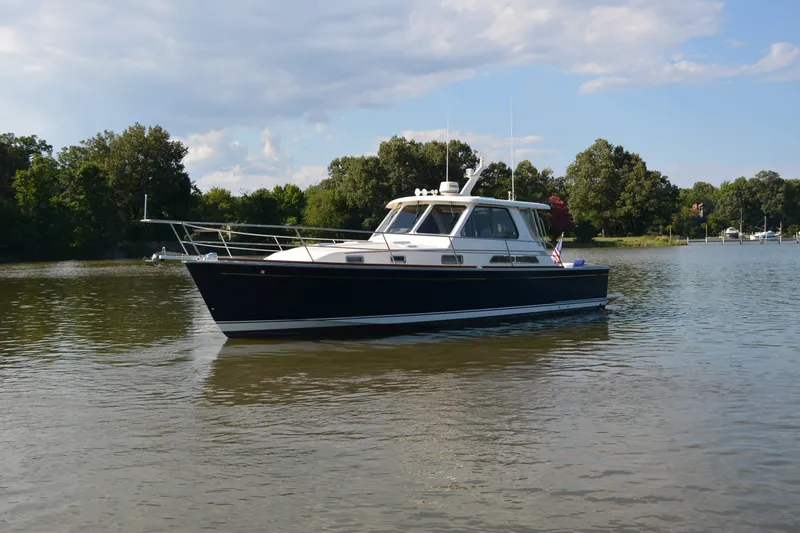 Slide: The Image of 2005 Sabre 38 Express yacht cruising on a calm river with lush green trees. - 6
