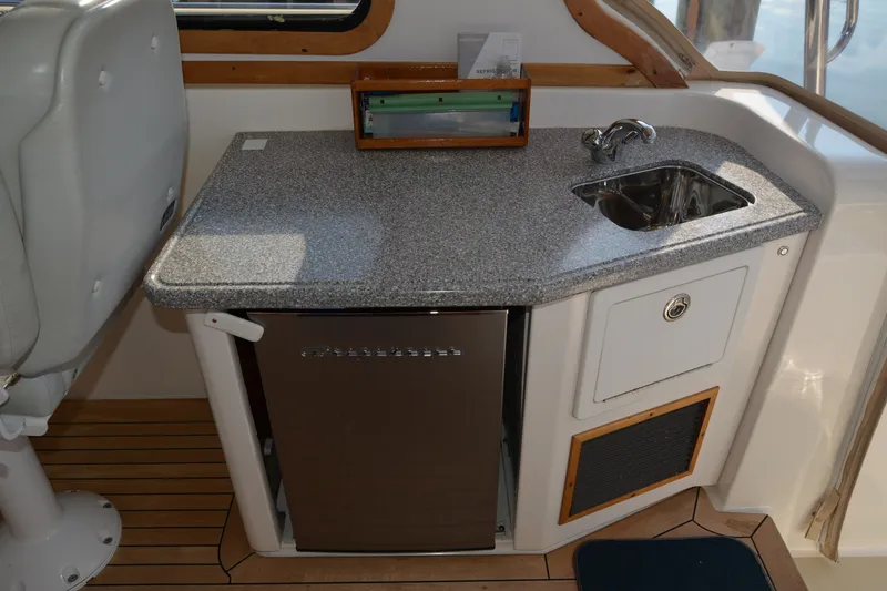 Slide: The Image of 2005 Sabre 38 Express yacht interior with kitchenette, featuring sink and mini fridge. - 57