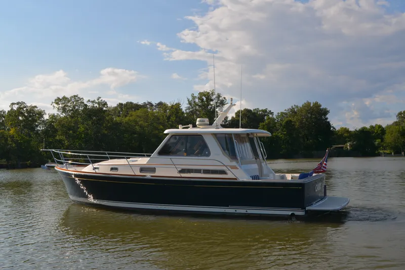 Slide: The Image of 2005 Sabre 38 Express yacht cruising on a serene lake with trees in the background. - 1