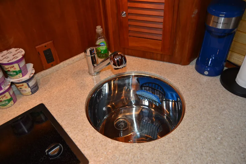 Slide: The Image of Compact kitchen sink area in 2005 Sabre 38 Express yacht with oatmeal cups and cleaning supplies. - 71