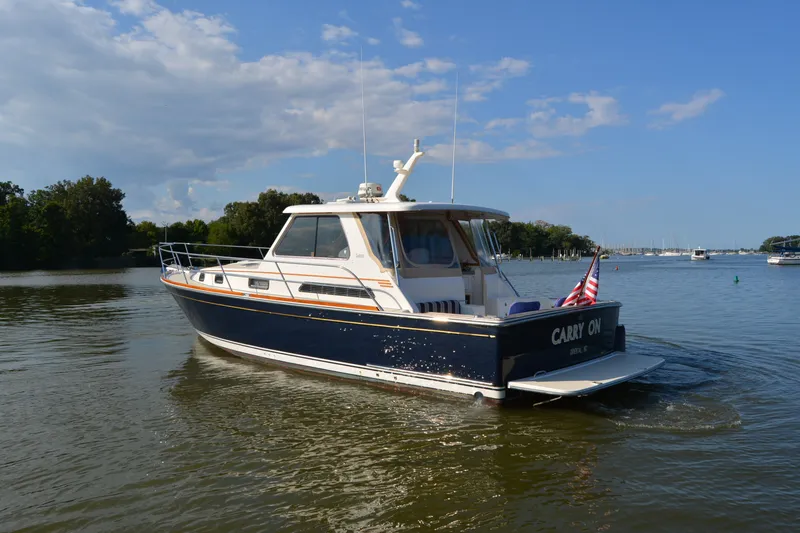 The Image of 2005 Sabre 38 Express boat cruising on a calm lake under a clear blue sky. - 0