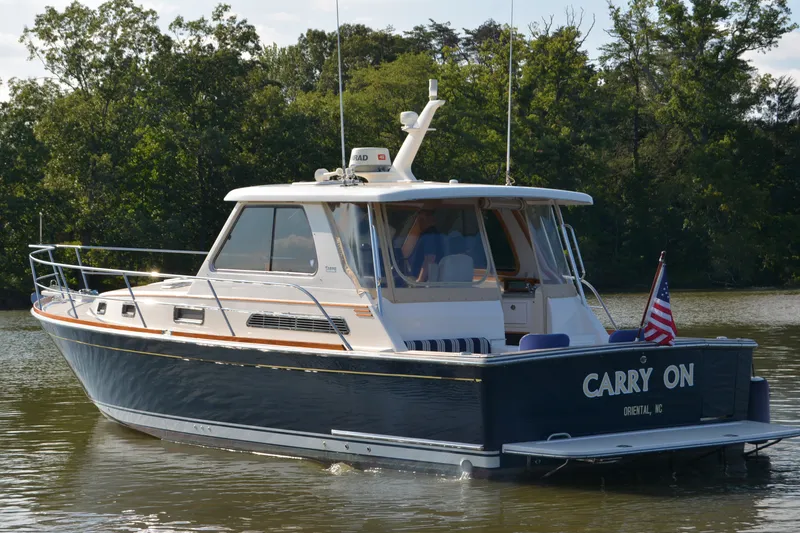 Slide: The Image of 2005 Sabre 38 Express boat named "Carry On" on a calm lake. - 2