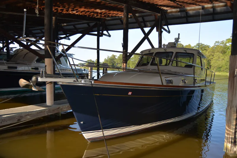 Slide: The Image of 2005 Sabre 38 Express yacht docked in a covered marina, reflecting on calm water. - 114