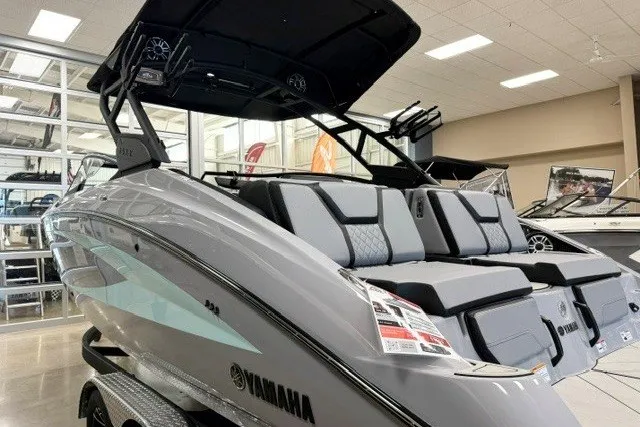 Slide: The Image of 2026 Yamaha Boats 255XD in showroom, sleek design, gray exterior, modern seating. - 2