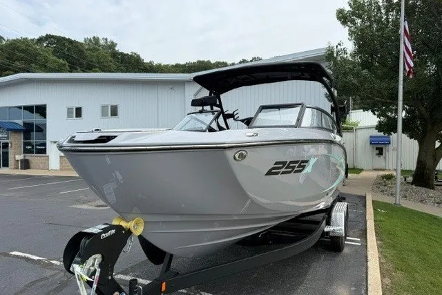 Slide: The Image of 2026 Yamaha Boats 255XD on trailer, parked outside a building with American flag. - 25