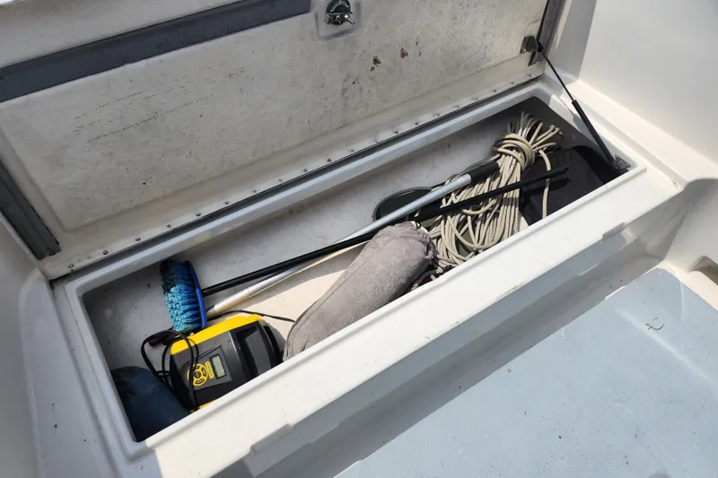 Slide: The Image of Storage compartment of a 1999 World Cat 246 SF boat with cleaning tools and rope. - 13