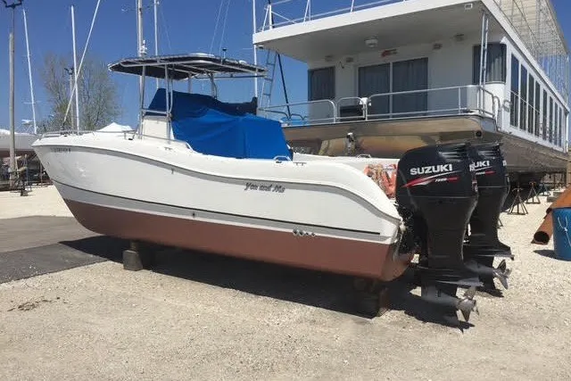 Slide: The Image of 1999 World Cat 246 SF boat with twin Suzuki outboard motors, parked on a gravel lot. - 2