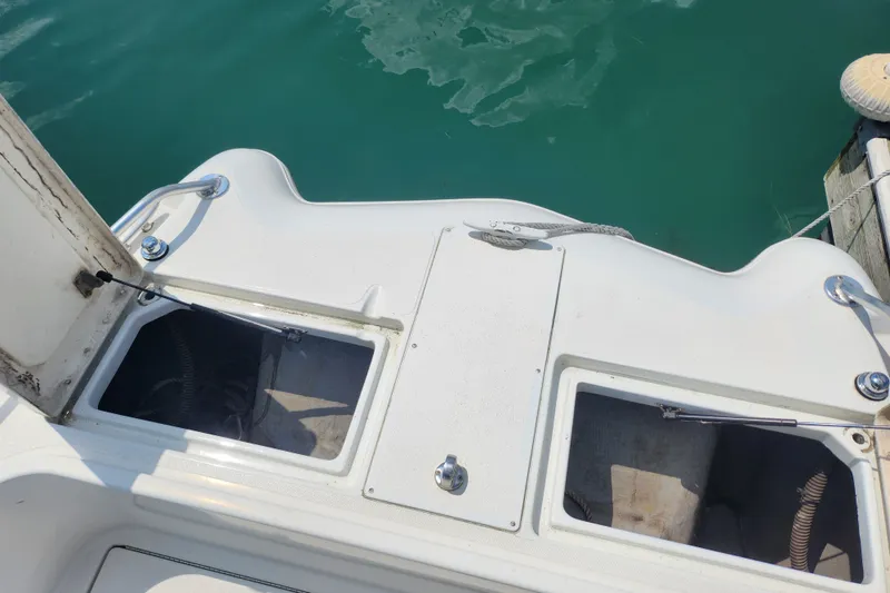Slide: The Image of 1999 World Cat 246 SF boat deck with storage compartments, docked on clear water. - 7