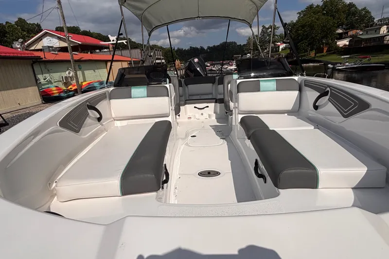 Slide: The Image of 2026 Tahoe T21 boat interior with spacious seating and canopy, docked near colorful buildings. - 2
