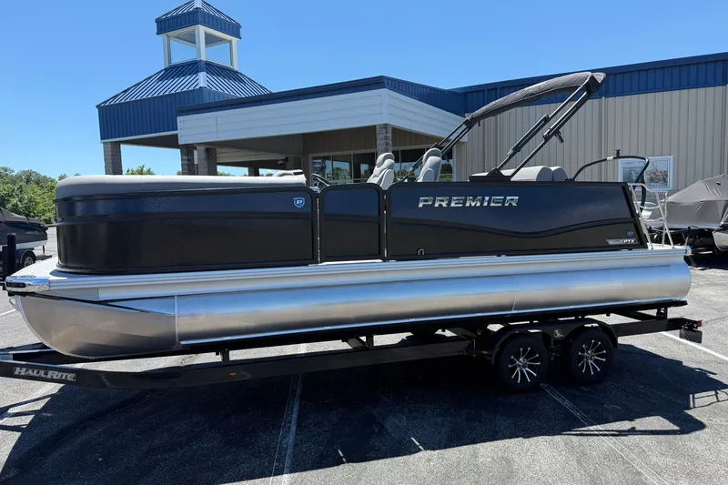 Slide: The Image of 2026 Premier 230 Sunsation RL pontoon boat on trailer, parked outside a building. - 4