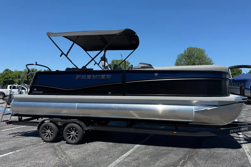 The Image of 2026 Premier 230 Sunsation RL pontoon boat on trailer, parked outdoors under clear blue sky. - 1