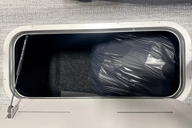 Slide: The Image of Storage compartment of 2027 Bennington 24 M Open Fastback Quad Bench, featuring a black bag. - 16