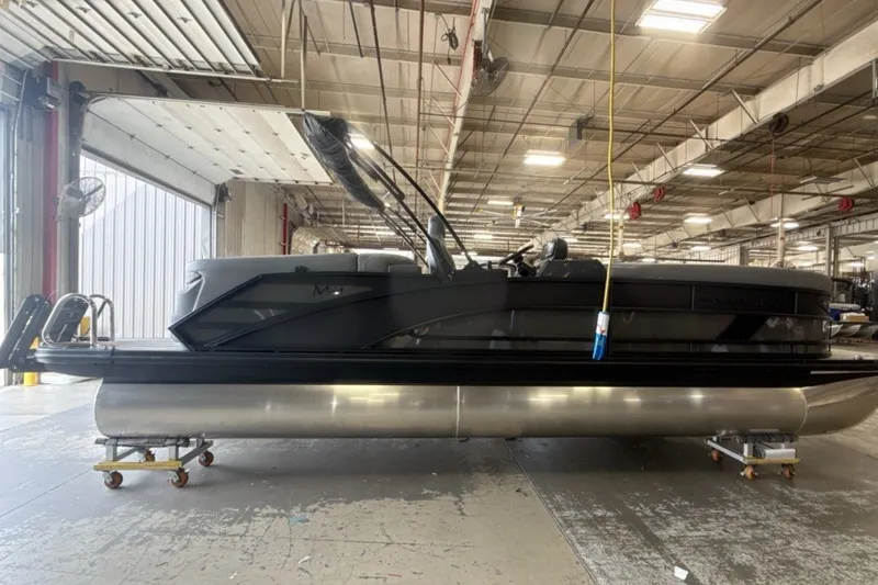 Slide: The Image of 2027 Bennington 24 M Open Fastback Quad Bench pontoon boat in a warehouse setting. - 1