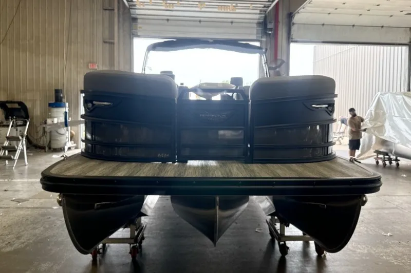 Slide: The Image of 2027 Bennington 24 M Open Fastback Quad Bench pontoon boat in a warehouse. - 2