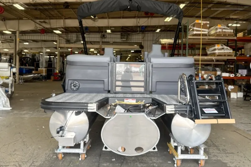 Slide: The Image of 2027 Bennington 24 M Open Fastback Quad Bench pontoon boat in a warehouse setting. - 7