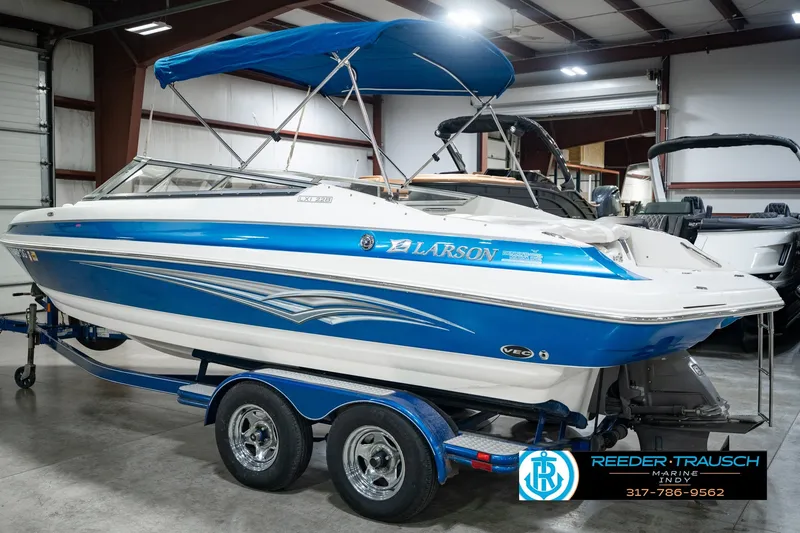 Slide: The Image of 2007 Larson LXi 228 Wakeboard Edition boat in showroom, blue and white design, on trailer. - 10