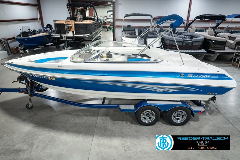 The Image of 2007 Larson LXi 228 Wakeboard Edition boat in showroom, blue and white design, on trailer. - 0