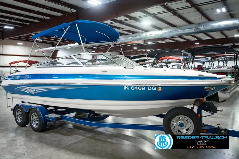 Slide: The Image of 2007 Larson LXi 228 Wakeboard Edition boat in showroom, blue and white design, on trailer. - 5