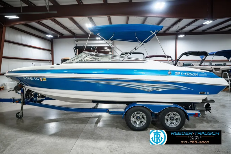 Slide: The Image of 2007 Larson LXi 228 Wakeboard Edition boat with blue and white design in a showroom. - 12