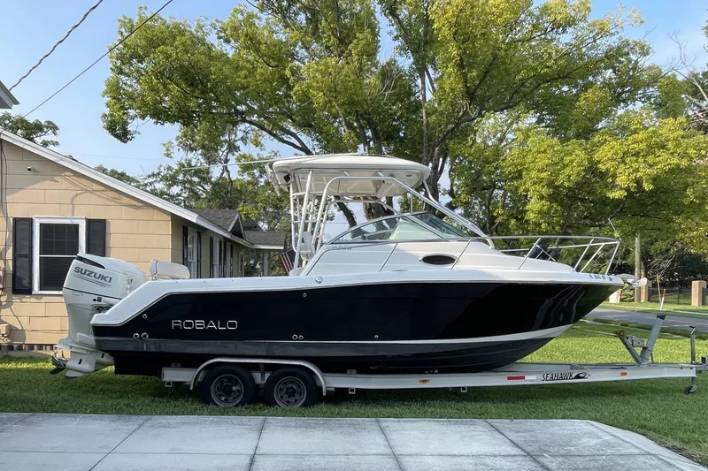The Image of 2007 Robalo R265 Walkaround boat on trailer, parked in a residential yard. - 0