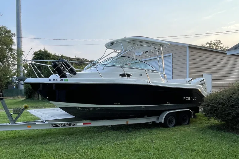 Slide: The Image of 2007 Robalo R265 Walkaround boat on trailer, parked on grass near a building. - 2