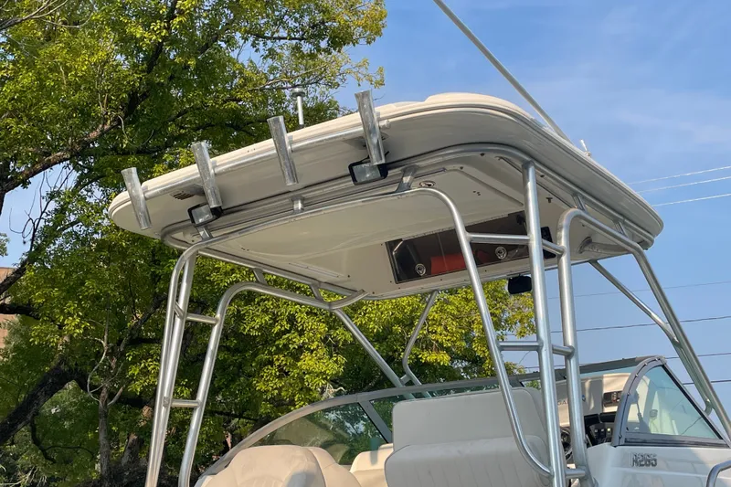 Slide: The Image of 2007 Robalo R265 Walkaround boat with T-top and rod holders, under clear blue sky. - 6