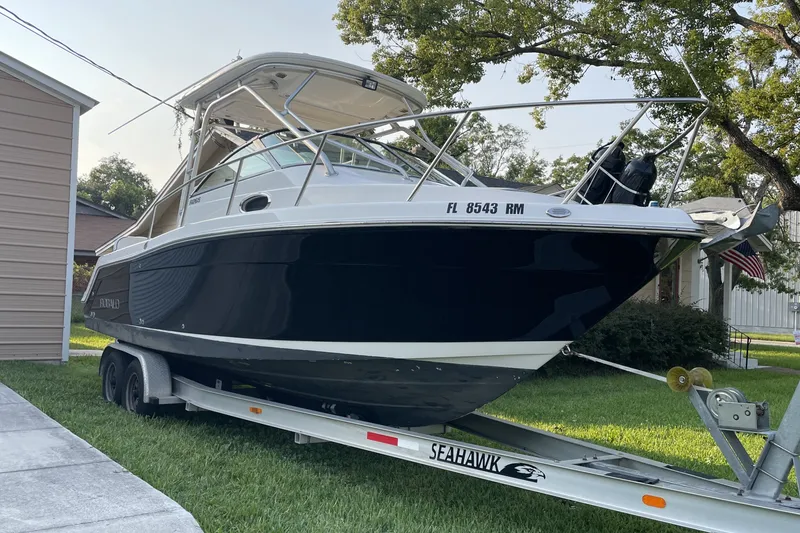 Slide: The Image of 2007 Robalo R265 Walkaround boat on trailer, parked in a grassy yard. - 1