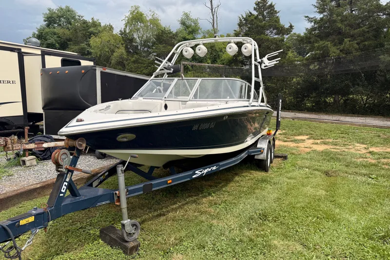 Slide: The Image of 2004 Supra Launch SSV boat on trailer, parked on grass near trees and trailers. - 5