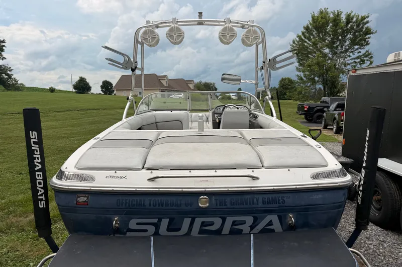 Slide: The Image of 2004 Supra Launch SSV boat with tower speakers, parked on grass. - 3