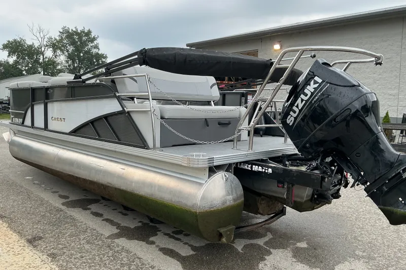 Slide: The Image of 2023 Crest Classic DLX 220 pontoon boat with Suzuki outboard motor, parked outdoors. - 3