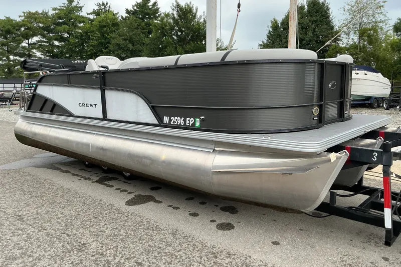 The Image of 2023 Crest Classic DLX 220 pontoon boat on trailer, parked outdoors. - 1