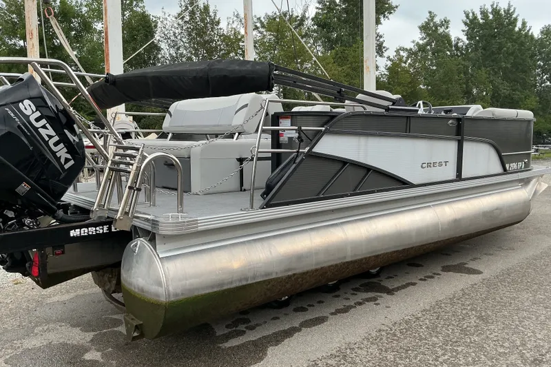 Slide: The Image of 2023 Crest Classic DLX 220 pontoon boat with Suzuki outboard motor, parked on a trailer. - 4
