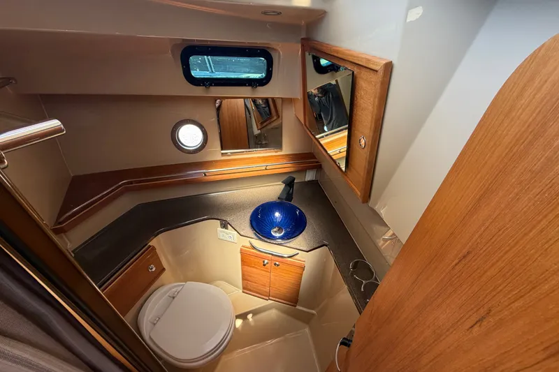 Slide: The Image of 2020 Ranger Tugs R-29 S bathroom with wooden cabinetry, round window, and blue sink. - 21