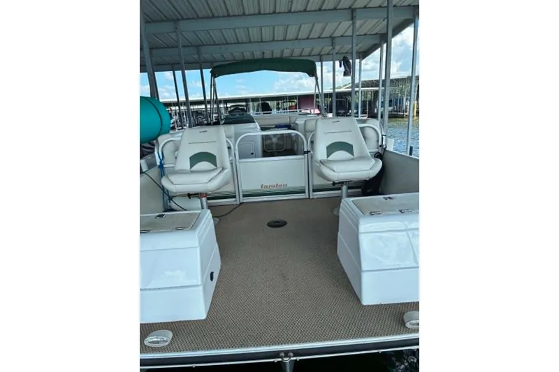 Slide: The Image of 2001 Landau DX 24 pontoon boat interior with seating and storage under a covered dock. - 7