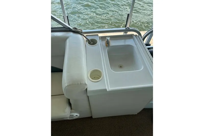 Slide: The Image of 2001 Landau DX 24 boat interior with sink and cup holders by the water. - 2
