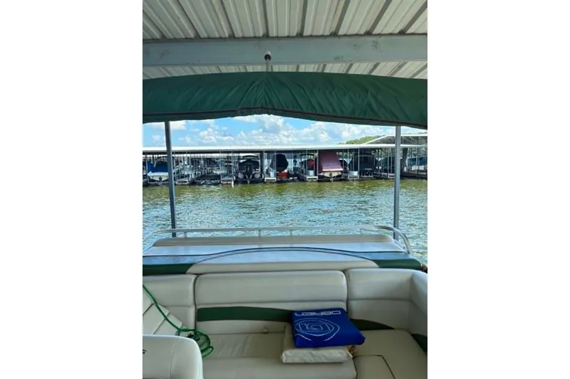 Slide: The Image of 2001 Landau DX 24 boat interior with marina view, featuring green canopy and seating. - 6