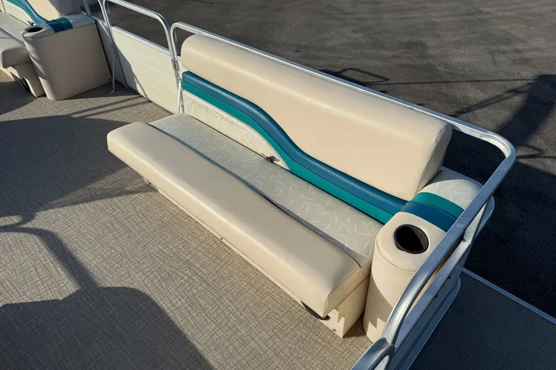 Slide: The Image of 1998 Lowe Family 245 boat seating with beige and teal upholstery, featuring a cup holder. - 11
