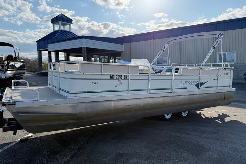 Slide: The Image of 1998 Lowe Family 245 pontoon boat parked outdoors under a sunny sky. - 6