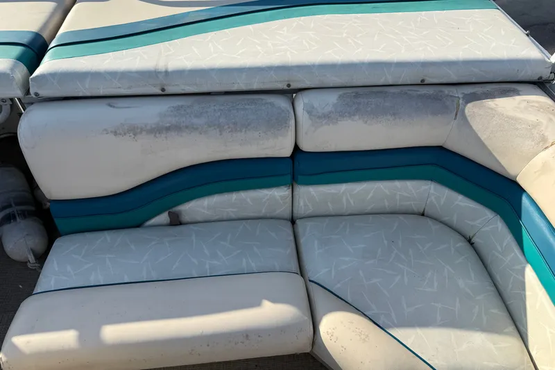 Slide: The Image of White and teal seating on a 1998 Lowe Family 245 boat, showing wear and discoloration. - 16
